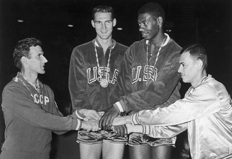 (Original Caption) Jerry West (second from left) and teammate Oscar Robertson (third left), representing the U.S.A. basketball players in the Rome Olympics, are congratulated by a representative from Russia (l) which finished second and a representative from Brazil (r) which finished third in the basketball tourney. The United States team finished unbeaten.